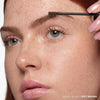  Soft Brown | Volumizing Tinted Brow Gel -Model Holding Product Wand